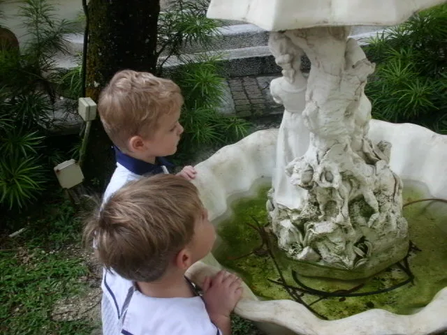 Children looking closely at an outdoor garden fountain.