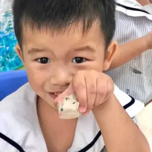 Nursery 2 child holding a small clay figurine during creative learning